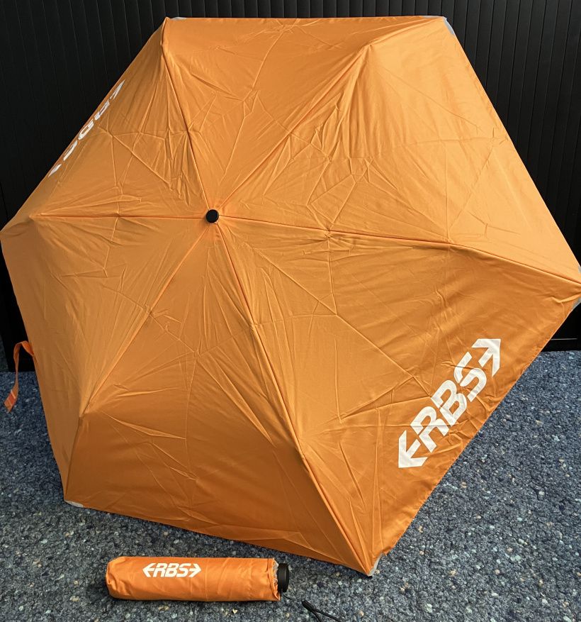 oranger RBS-Regenschirm aufgespannt und im Taschenformat