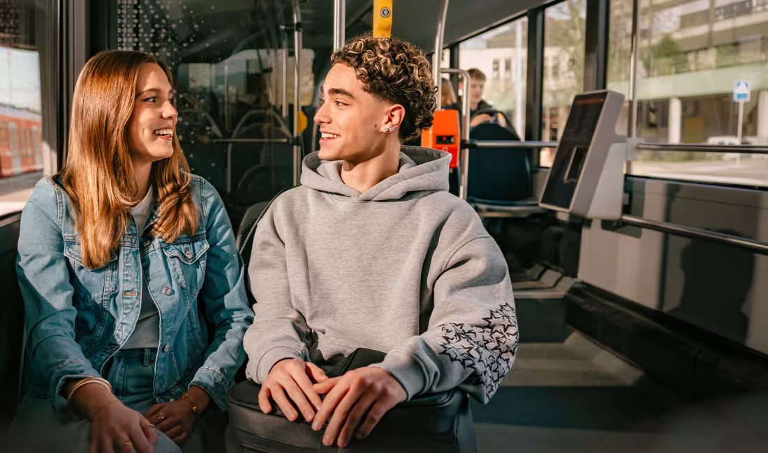 Zwei junge Fahrgäste sitzen im RBS Bus und unterhalten sich während der Fahrt.