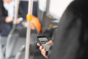 Mann im Bus mit Smartphone in der Hand - oranger Button oben links