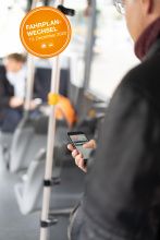 Mann im Bus mit Smartphone in der Hand - oranger Button oben links