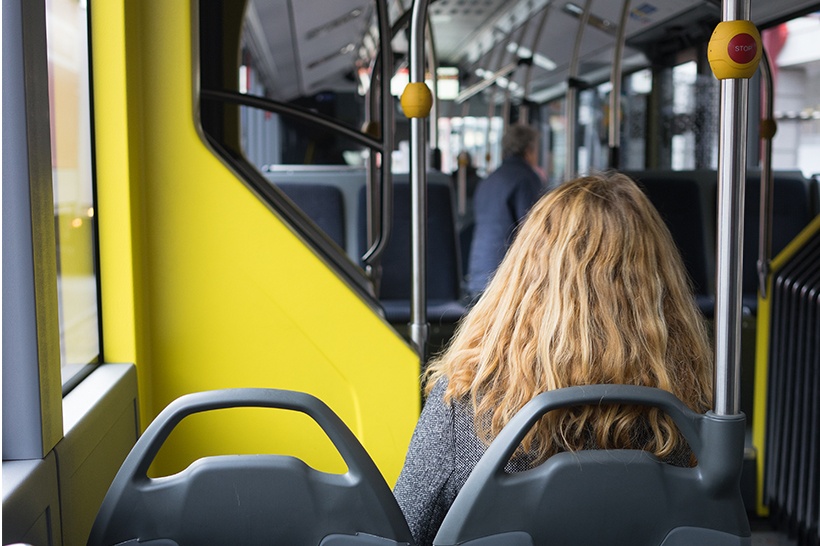 eine blonde Frau sitzt in einem RBS Bus. Nur ihr Hinterkopf ist zu erkennen. Der Platz neben ihr ist frei