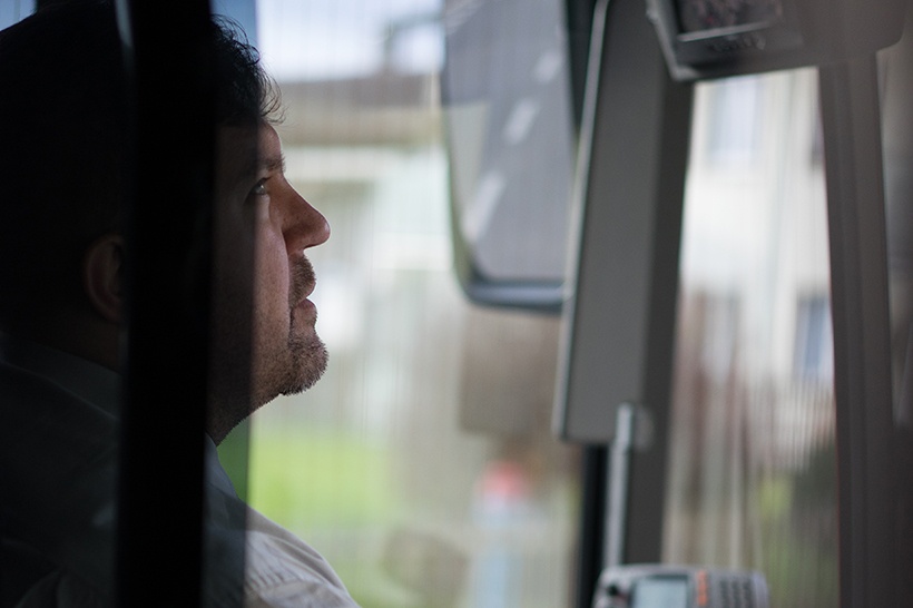 Ein Buschauffeur in einem RBS-Bus schaut in seinen Rückspiegel. Er ist leicht verdeckt und nur der vordere Teil seines Gesichts ist zu erkennen. 