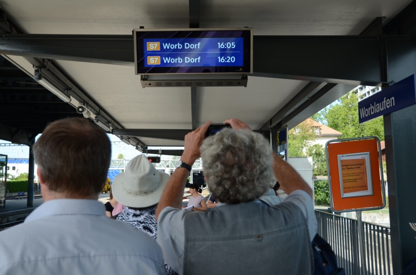 Eine Testperson mit einer Sehbeeinträchtigung fotografiert den Abfahrtsmonitor