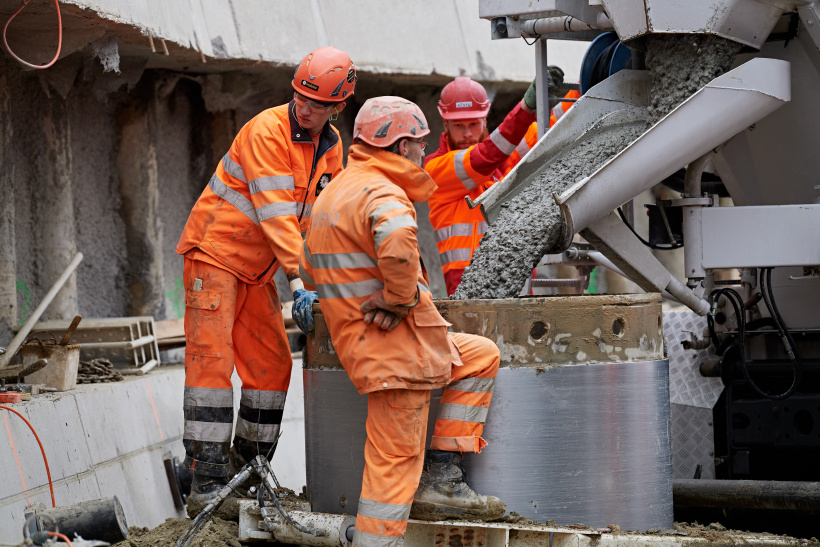 Drei Bauarbeiter betonieren ein Borhphal